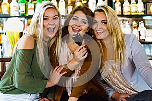 Women in bar singing karaoke