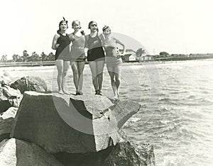 Women in bathing suits posing on rock photo