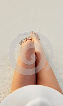 Women Beautiful Sexy Legs on the Beach. Skin care and Protection Sun. Spa Concep
