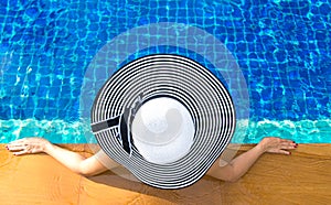 Women big hat lifestyle relaxing near luxury swimming pool sunbath, summer day at the beach resort in the hotel.