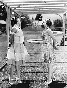 Women biting apples on strings at Halloween