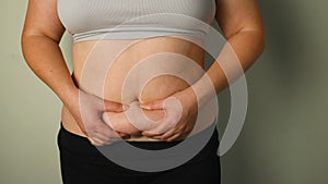 Women body fat belly. Obese woman hand holding excessive belly fat. Fat woman trying to zip up her jeans pants