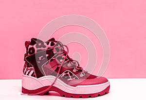 Women boots magenta color, trendy fashionable shoes on pink background. Copy space.
