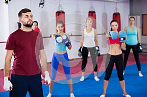 women are boxing and doing kick with coach