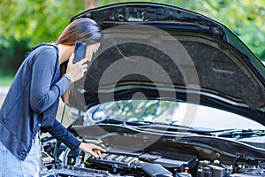 Women and broke down car on the road and she use mobile phone.