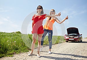 Women with broken car hitchhiking at countryside