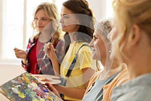 Women with brushes painting at art school