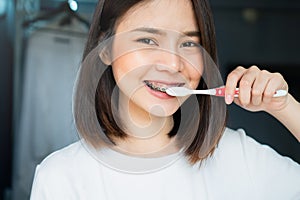 Women are brushing teeth that wear braces, in a toilet. Must maintain good oral health.