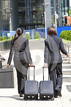 Women Business Travellers With Rolling Suitcases