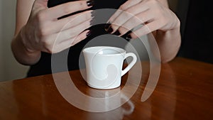 Women in a cafe with a cup of coffee removes a wedding ring from a finger, throws it into a cup and leaves
