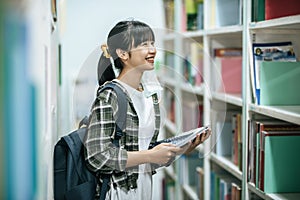 Women carrying a backpack and searching for books in the library