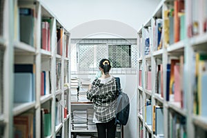 Women carrying a backpack and searching for books in the library