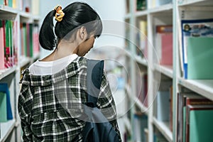 Women carrying a backpack and searching for books in the library