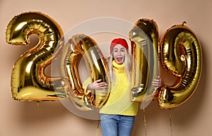 Women celebrating New Year party happy laughing in yellow sweater blouse with 2019 gold balloons