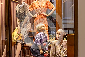 Women and child mannequins in retro style casual clothes on the clothing retail store window in the shopping mall.