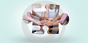 Composite image of women in a circle putting their hands together