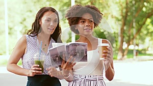 Women with city guide and drinks on street