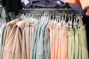 Women clothing in pastel colors on hangers in a boutique store. Sale of women's clothing. Casuale style photo