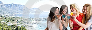 Women with cocktails against blurry coastline