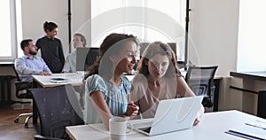 Women colleagues talking looking at laptop, discuss task at workplace