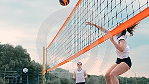 Women Competing in a Professional Beach Volleyball Tournament. A defender attempts to stop a shot during the 2 women