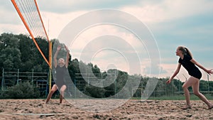 Women Competing in a Professional Beach Volleyball Tournament. A defender attempts to stop a shot during the 2 women