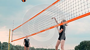 Women Competing in a Professional Beach Volleyball Tournament. A defender attempts to stop a shot during the 2 women