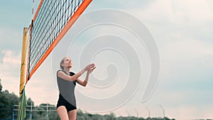 Women Competing in a Professional Beach Volleyball Tournament. A defender attempts to stop a shot during the 2 women