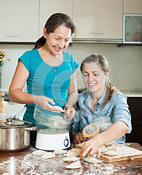 Women cooking meat pasties with electric steamer