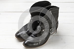 Women cowboy boot. Black leather shoes on a white wooden table. Composition of clothes. Flatlay