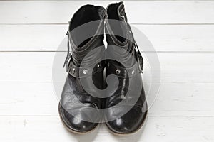 Women cowboy boot. Black leather shoes on a white wooden table. Composition of clothes. Flatlay