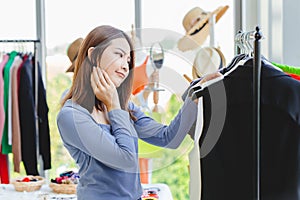 Women customer thinking and hesitate to choosing clothes black color looking for new shirt in fashion shop