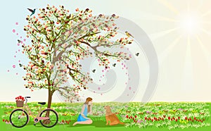 Women and dogs sit under the flower tree. There are bicycles beside them. There are grasslands and flowers in the background.