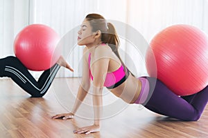 Women doing exercise with fit ball in gym class