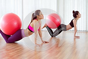 Women doing exercise with fit ball in gym class