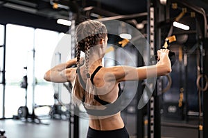 Women doing pull ups training arms with trx fitness straps in the gym. Upper body training. Back view.