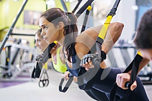 Women doing push ups training arms with trx