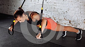 Women doing push ups training arms with trx straps in gym