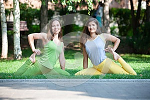 Women doing yoga outdoors in the park.