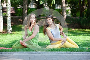 Women doing yoga outdoors in the park.