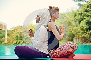 Women doing yoga by the poolside