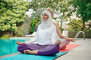 Women doing yoga by the poolside