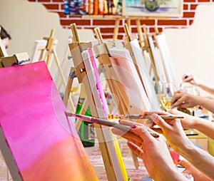 Women drawing on canvases during masterclass in the art studio, hands only