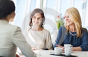 Women drinking coffee and talking at restaurant