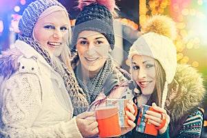 Women drinking mulled wine in mugs on German Christmas Market