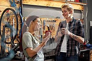 Women drinking tea and talking in bicycle workshop