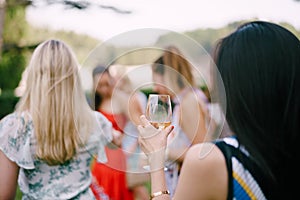 Women with drinks in glasses stand in nature