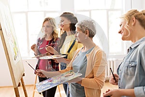 Women with easel and palettes at art school