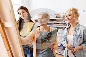 Women with easel and palettes at art school