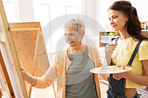 Women with easels and palettes at art school